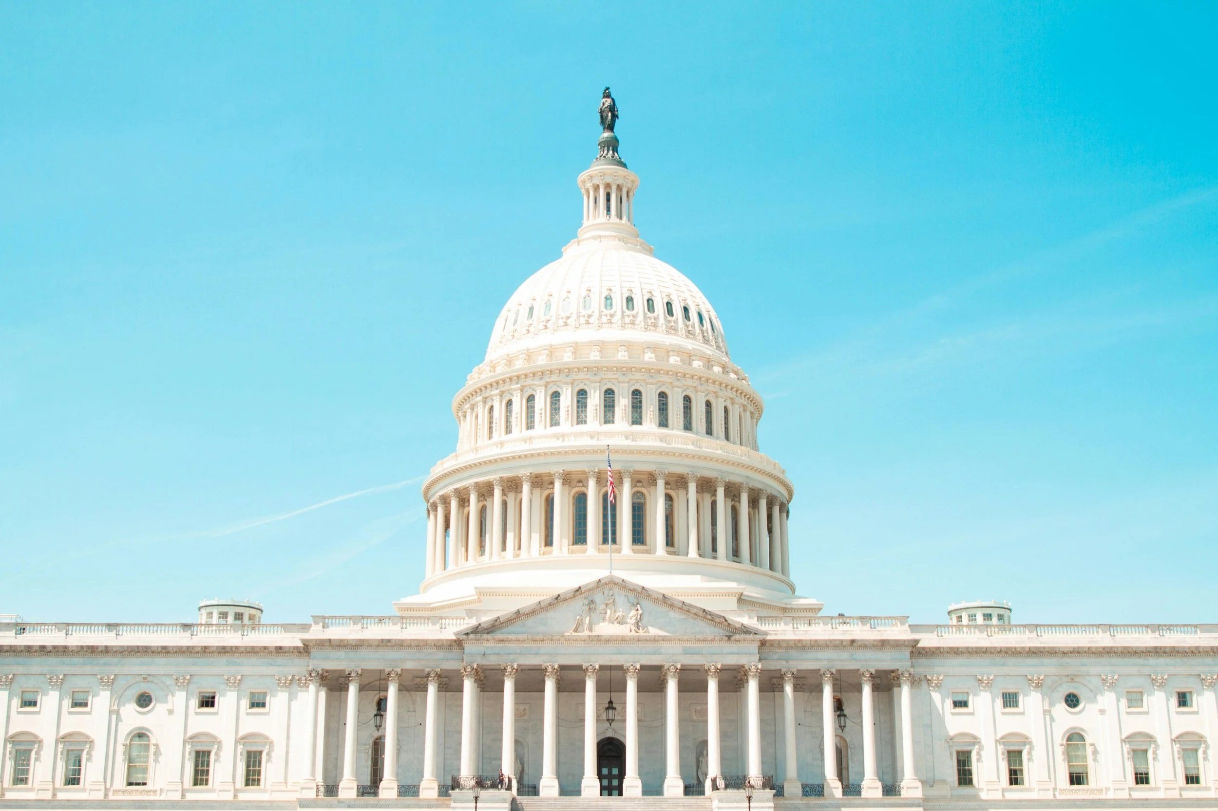 Front view of the United States Capitol building with a clear blue sky in the background.